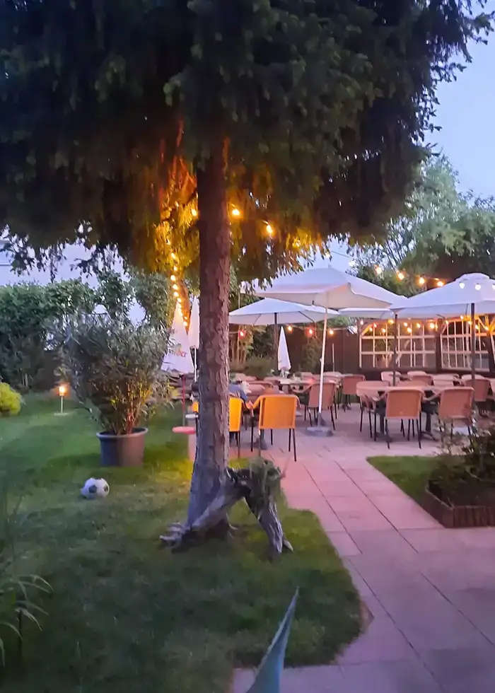 Biergarten im Innenhof am Abend mit Blick in den Garten